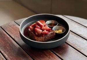 A bowl of french toast with strawberries and syrup