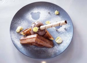 Belgian waffle with chocolate gelato and wafer roll on a blue plate