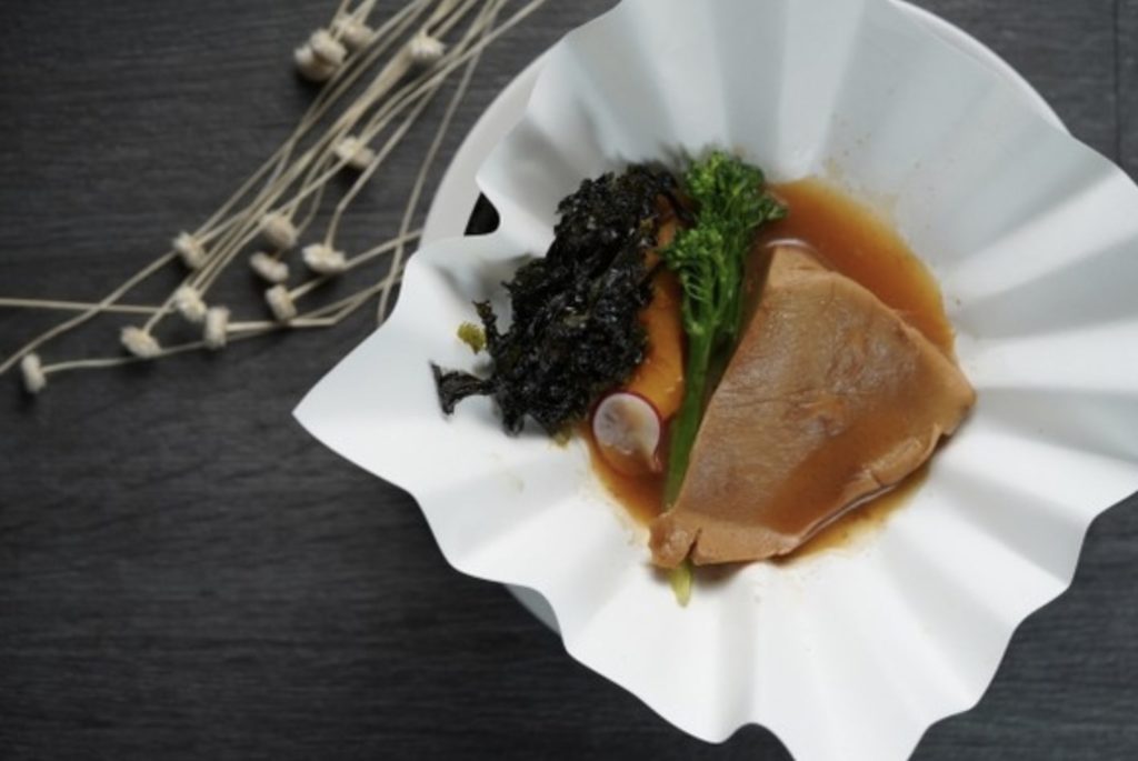 A plate with braised mushroom in sauce and green garnish
