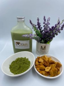 A bottle of green tea latte next to a bowl of green tea powders and honeycomb