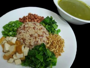 A plate of brown rice, tofu, green vegetables, and peanuts