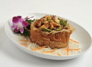 A plated vegetarian meal with edible flowers, garnish, and peanuts