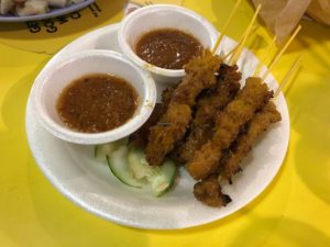 A plate of vegan chicken satay with two bowls of sauces