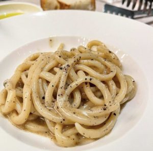 Italian caccio e pepe pasta with pepper on a white plate