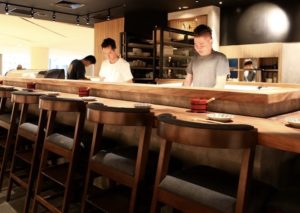 A sushi bar with three sushi chefs
