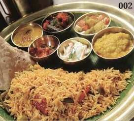 A plate of Indian biryani rice with assorted sauces