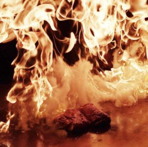 Two pieces of tenderloin meat being flambeed on a teppanyaki table