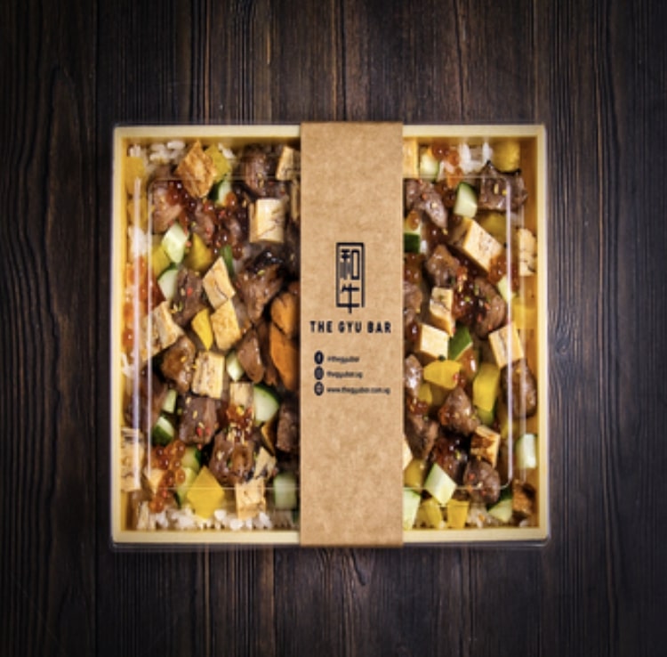 A bento box filled with Japanese wagyu, vegetables, and garnish